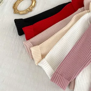 Flat lay detail showing vertical rib-knit texture of children's sweaters in multiple colors