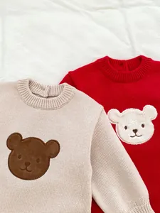 Détail du tricot doux et de l'écusson ours en peluche mignon sur la barboteuse bébé