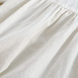 Gedetailleerd zicht op witte baby romper met fijne rimpels en katoen-linnen textuur