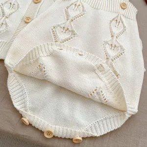 Detail showing hollow diamond knit pattern and wooden buttons on cream baby romper
