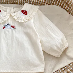 Dettaglio del colletto a balze con ricamo a coniglio e fungo su camicia da neonato