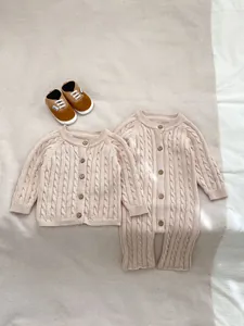 Dettaglio del set pagliaccetto neonato a maglia con trecce e bottoni in legno