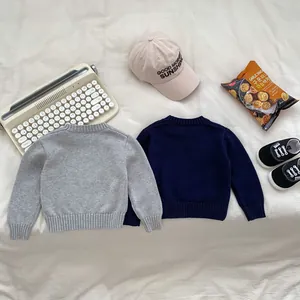 Flat lay of soft knit sweaters for kids in grey and navy with ribbed collar and cuff details
