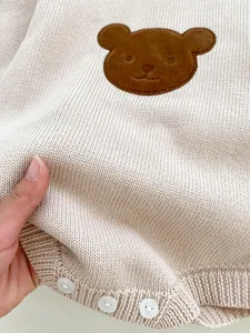 Gros plan sur le tissu doux en tricot pour bébé avec patch ours et détails de boutons