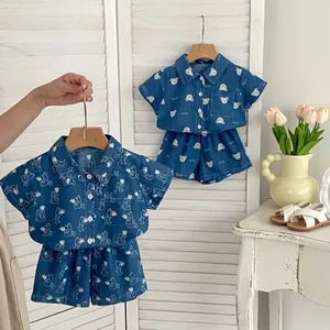 Dettaglio del set estivo in denim per bambini con stampe di piante e orsi su camicie corte