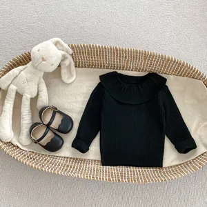Detailed view of girls' black knit sweater featuring an elegant large ruffled collar design