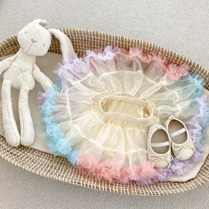Close-up of a rainbow tutu skirt with beige infant shoes and a plush rabbit in a basket