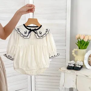 Detail van babyromper met vintage geborduurde kraag en zwarte strik van lint
