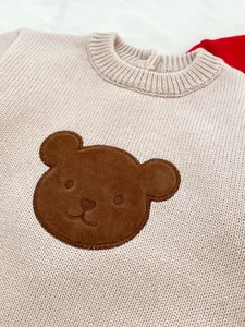Gros plan détaillé d'une barboteuse en tricot pour bébé avec écusson ours brodé