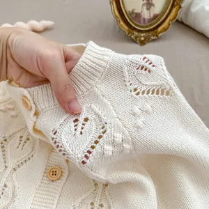 Close-up of baby pointelle knit cardigan with bobble details and wood buttons