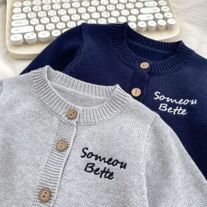Dettagli di cardigan in maglia blu e grigio con bottoni in legno e ricamo sul petto