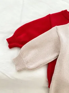 Détail de barboteuses en tricot rouge et beige avec poignets côtelés et texture douce