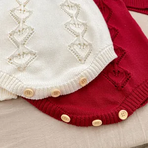 Detail of baby knitted rompers showing hollow heart patterns and vintage wood buttons
