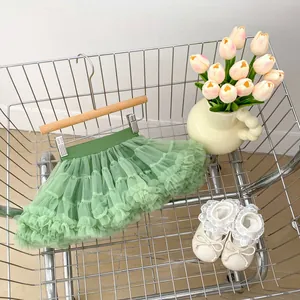 Detail of green layered mesh tutu skirt and lace baby shoes in a shopping cart
