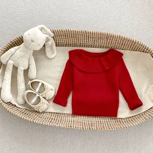 Close-up of red knit sweater featuring a wide ruffle collar in a woven baby basket