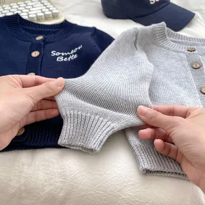Dettaglio ravvicinato dei polsini elastici in maglia e dei bottoni in legno per bambini