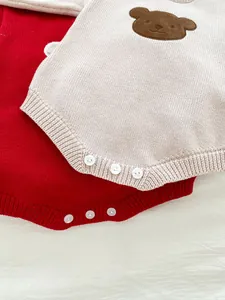 Détail de barboteuses en tricot pour bébé rouge et beige avec motif ours et boutons