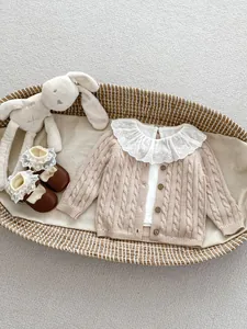 Close-up of baby knit cardigan with lace collar and matching brown infant shoes