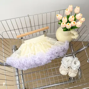 Detail view of a cream and lavender tutu skirt with matching lace-up baby shoes