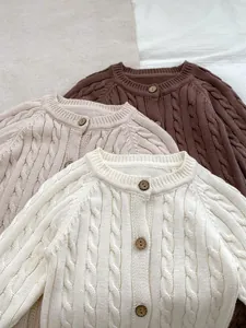 Dettaglio della maglia a trecce spesse e dei bottoni in legno sulle tutine neonato