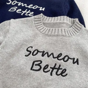 Close-up of crewneck knit sweater featuring 'Someone Better' cursive embroidery detail