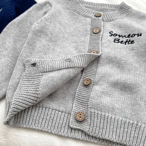 Dettaglio del cardigan grigio a maglia per bimbi con bottoni in legno e ricamo