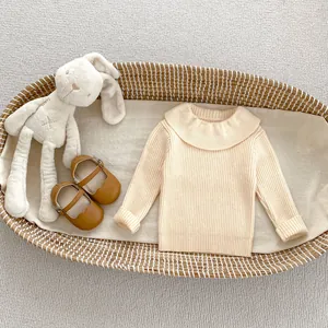 Detail of ribbed knit cream baby sweater with ruffled collar and brown Mary Jane shoes