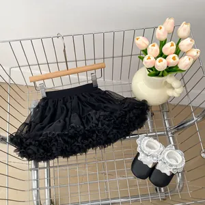 Detail view of black layered mesh tutu skirt and lace baby shoes in a metal basket