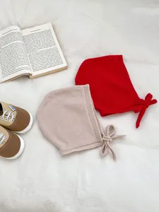 Gros plan de bonnets en tricot pour bébé avec nœuds et chaussures en toile sur tissu