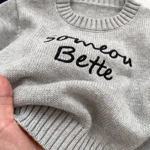 Light gray knit sweater for kids featuring someone Better embroidery and ribbed crew neck