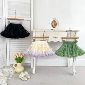 Detailed layered tutu skirts in black, cream and sage green on wooden hangers