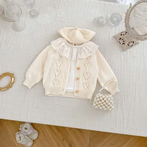 Detail of baby hollow knit cardigan with wooden buttons and lace collar shirt