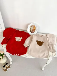 Gros plan détaillé de barboteuses en tricot pour bébé en rouge et beige avec ours