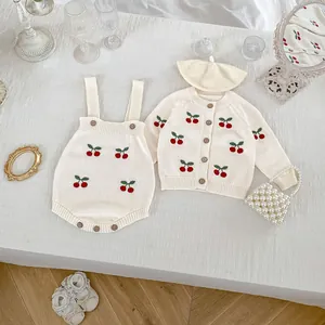 Dettaglio del cardigan in maglia per neonato con ricami a ciliegia e bottoni in legno
