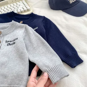 Dettaglio cardigan in maglia con bottoni in legno e ricamo 'Someone Better'
