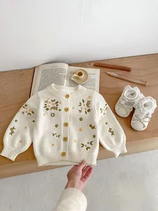 Detailopname van bloemenborduurwerk op baby katoenen vest met bruine knopen