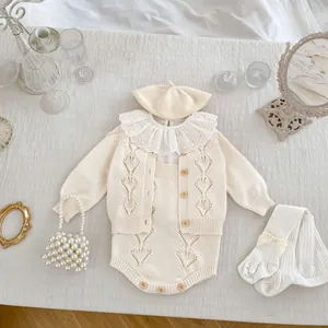 Detailed flat lay of cream knit baby set with openwork cardigan and lace romper