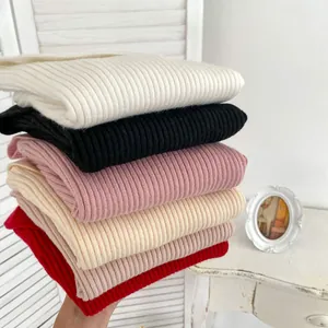 Detail of stacked ribbed knit sweaters in multi-colors showing soft texture and fabric
