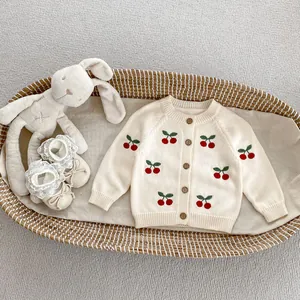 Dettaglio del cardigan in maglia crema per neonati con ricamo a ciliegia e peluche morbido