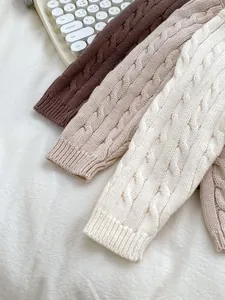 Close-up of cable knit texture on children's sweaters in brown, oatmeal, and cream tones