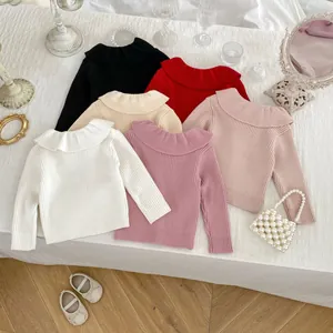 Flat lay of colorful ribbed knit girl sweaters featuring large ruffle collars and soft texture