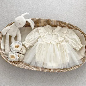 Detailed close-up of a cream baby romper dress with lace tutu and matching soft-sole shoes