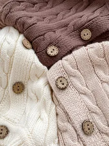 Detailed macro view of cable knit texture and wooden buttons on cotton cardigans