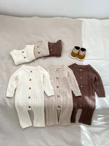 Dettaglio di pagliaccetti in maglia a trecce per neonati con bottoni in legno