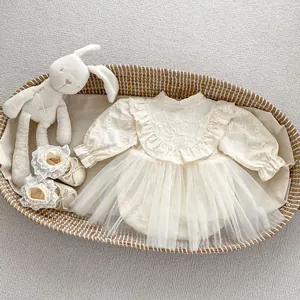 Detail view of baby girl romper with floral embroidery and tulle skirt in wicker cradle
