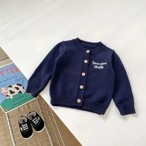 Dettaglio del cardigan in maglia blu scuro per bambini con bottoni in legno