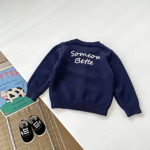 Dettaglio maglione in maglia blu scuro per bambini con ricamo di lettere bianche
