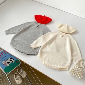 Detail of knitted baby romper set and beret showing soft texture in grey and beige