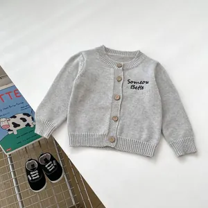 Dettaglio del cardigan in maglia grigio chiaro con ricamo e bottoni in legno bio