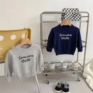 Detail of children's crew neck sweaters with ribbed cuffs and letter embroidery